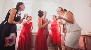 Wedding party in red and white dresses gathering in a bright indoor space.