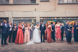 Wedding party lined up against an urban wall with bridesmaids in pink and coral dresses.