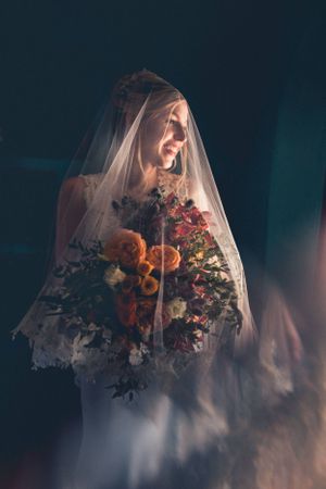 Ethereal bridal portrait with colorful floral bouquet viewed through delicate veil.