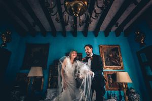 Wedding couple silhouetted in blue-lit room with ornate decor.