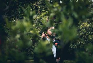Romantic wedding portrait through green foliage in natural garden setting.