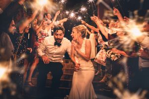 Wedding celebration with sparklers illuminating joyful dancing guests at night.