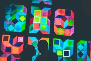 Colorful geometric neon patterns displayed on dark background creating vibrant light display.