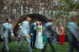 A line of wedding guests dancing together in an outdoor garden setting.