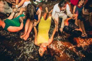 Wedding party guests dance energetically on the floor with confetti flying through the air.