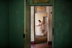 A white dress visible through doorways in an old green-walled building creates a dramatic composition.