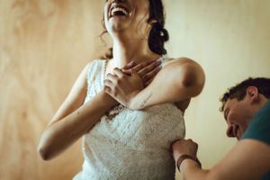 A bride in a white dress laughs joyfully during a candid wedding moment.
