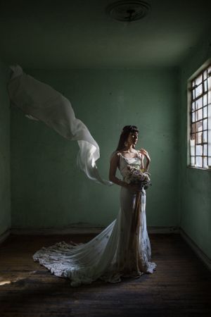 A dramatic bridal portrait with flowing veil in an empty mint green room.