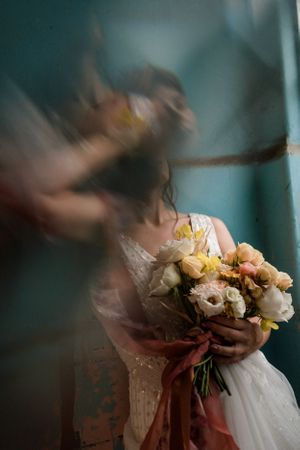 An artistic motion blur photo of a wedding bouquet with peach and cream colored flowers.