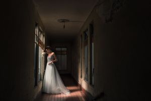 A moody bridal portrait in a dark hallway with natural light streaming through.