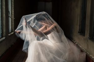 Moody bridal portraits through sheer veil in dark atmospheric setting.