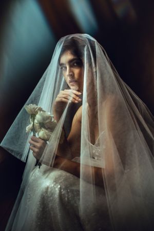 Dramatic close-up portraits of a bride wearing a sheer veil against dark moody background.