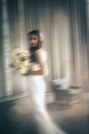 Artistic motion blur photograph of bride in white dress creating ethereal effect.