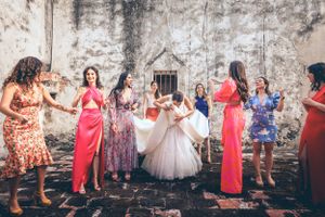 Wedding celebration with attendants in colorful dresses dancing around the bride.