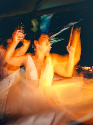 Motion blur photo capturing dancers in orange light creating ethereal effect.