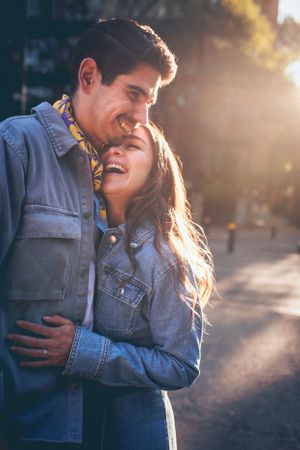 Couple embracing in warm sunset light wearing denim jackets outdoors.