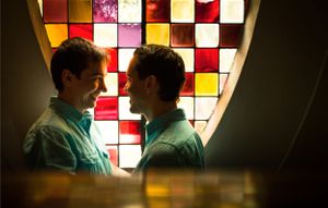 A silhouette portrait against a colorful stained glass window backdrop.