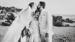Intimate wedding portrait on a rocky beach with flowing white veil.