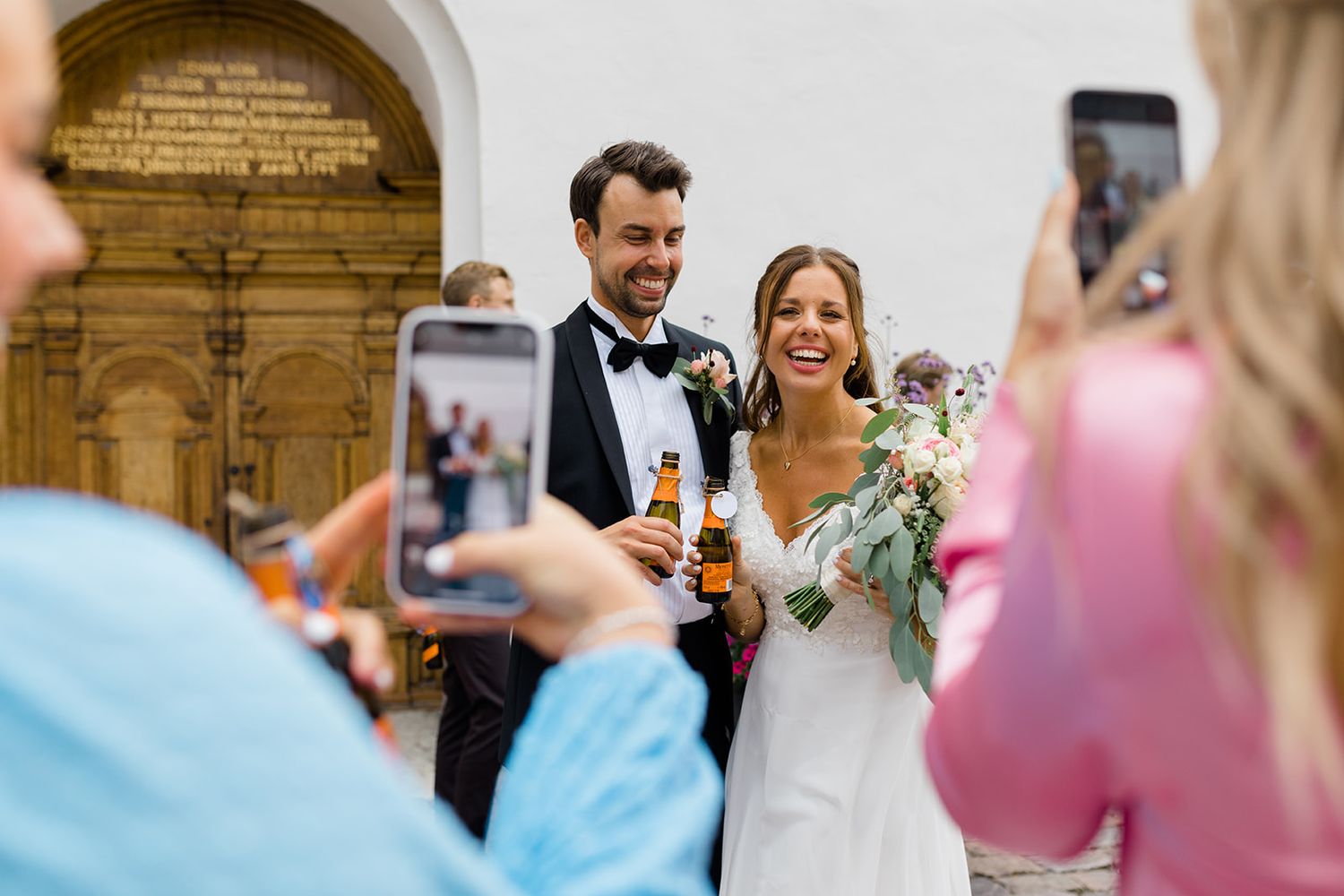 Wedding guests celebrate by blowing bubbles as newlyweds exit their ceremony.