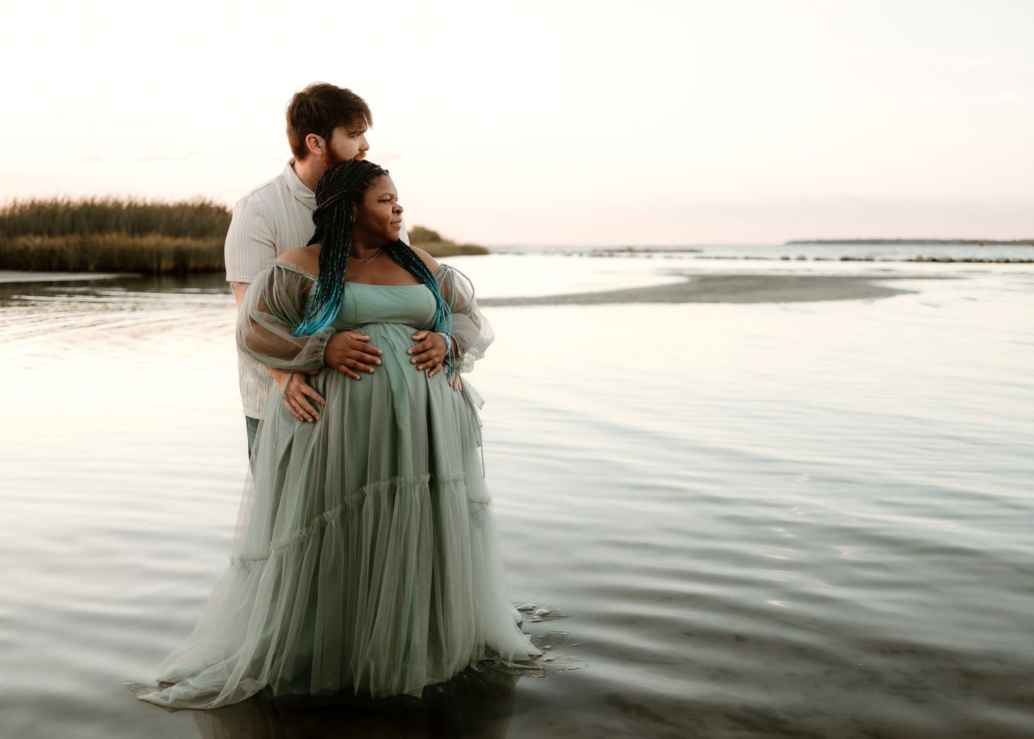 Maternity photography session at the beach during golden hour with flowing sage green dress.