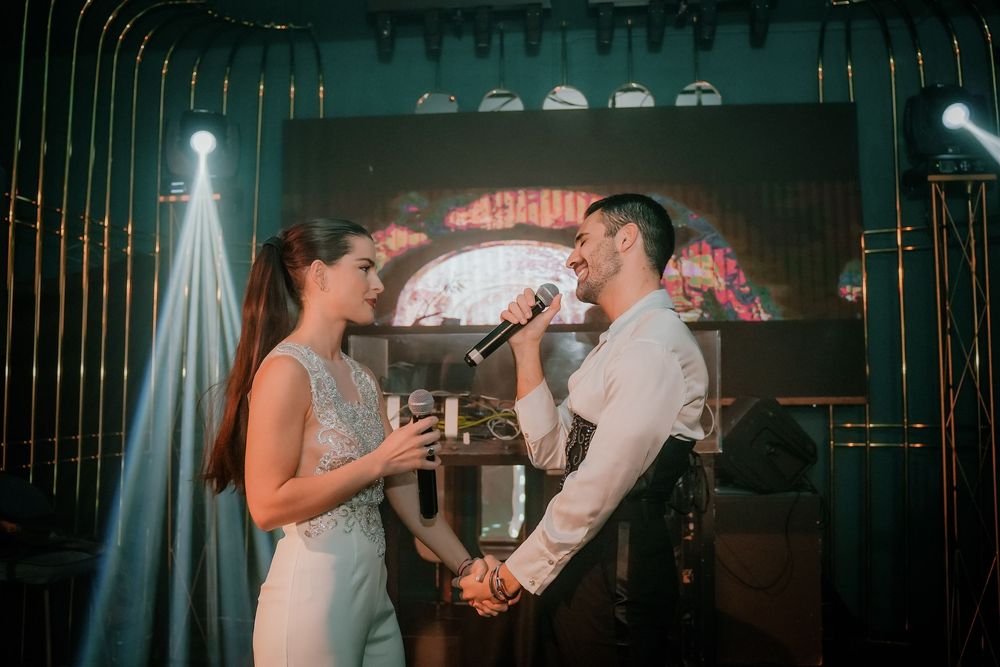 Pareja cantando en directo durante actuación en escenario con iluminación teatral