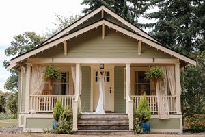 Craftsman style bungalow with covered front porch and white trim showcases classic architectural details in natural setting.