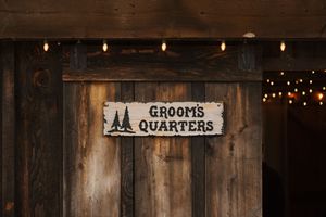 Rustic wooden barn door with metal hinges and weathered wood planks illuminated by string lights.