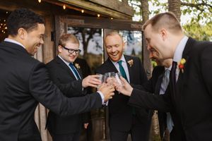 A group of formally dressed people laugh and interact during a social gathering at an outdoor event.
