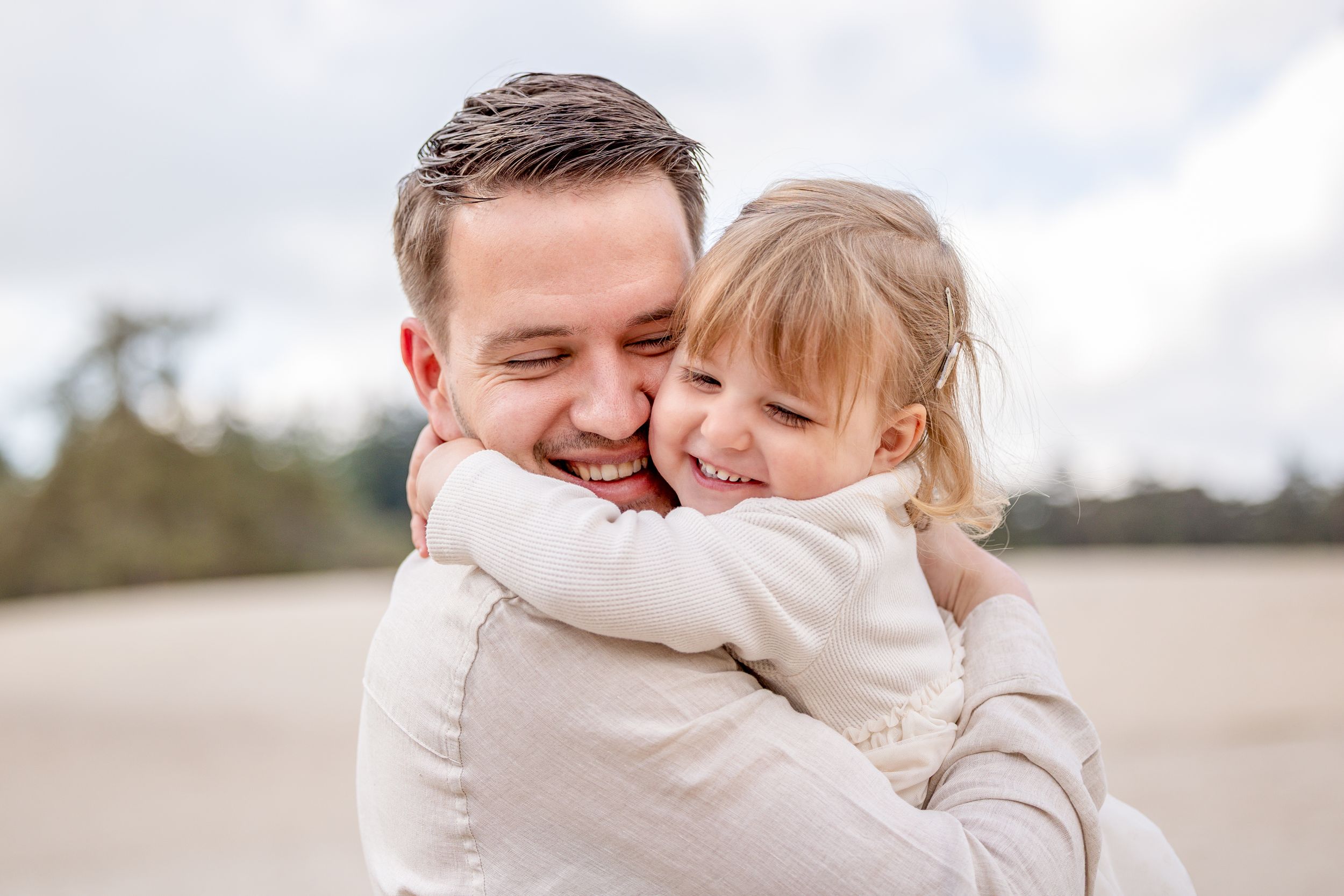 papa en dochter, knuffelend en met de ogen dicht tijdens een gezinsfotoshoot