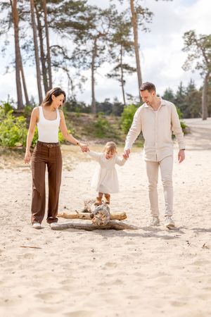 jong gezin met peuter meisje, lopend tussen haar ouders over een boomstam op de sahara.
