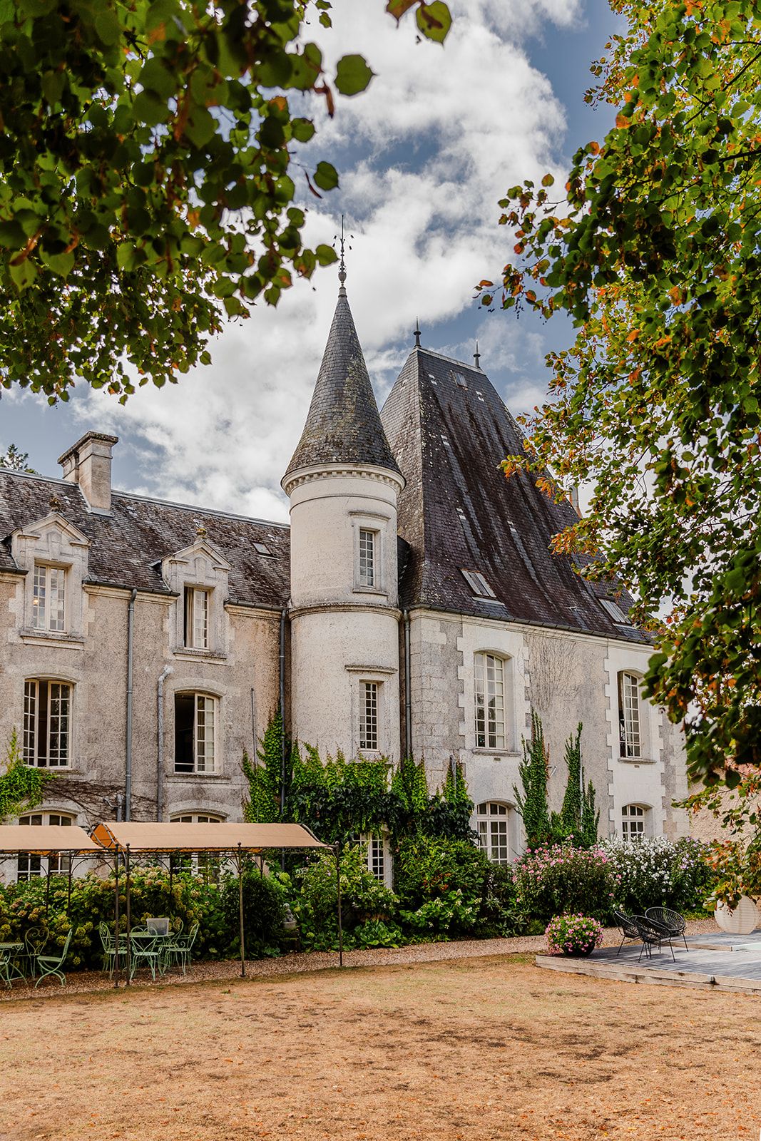 A panoramic view of a grand French chateau with pointed turrets and classic architecture set against a cloudy sky.