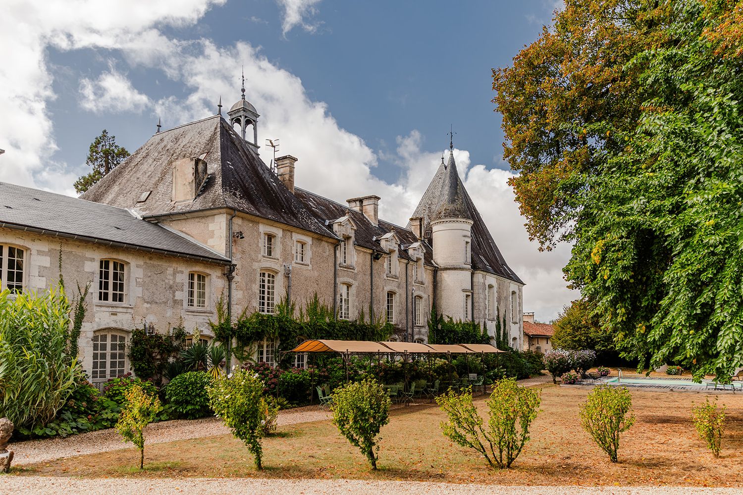 A panoramic view of historic stone buildings and trees along a quiet rural street in France.