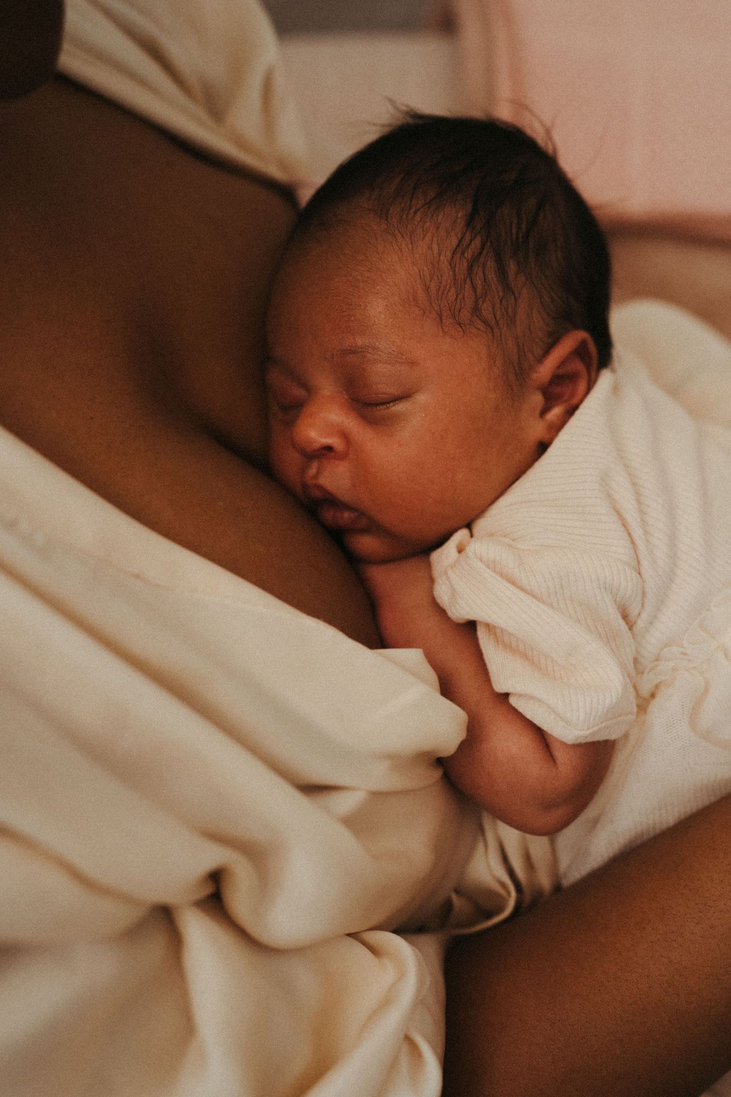 Close-up photos of a sleeping newborn baby in white clothing.