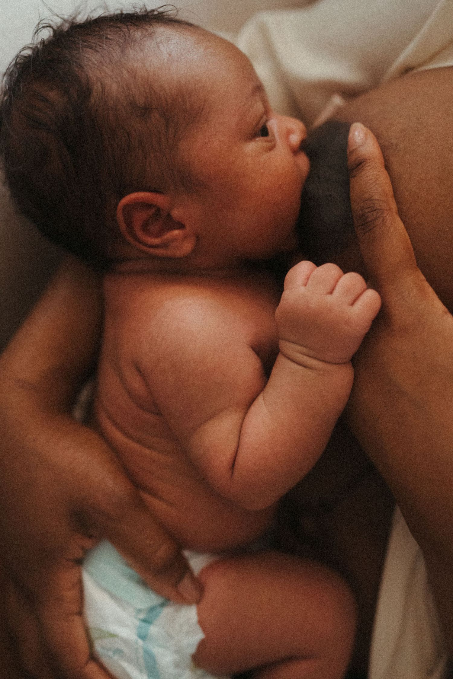Close-up shots of a newborn nursing in warm, intimate lighting.