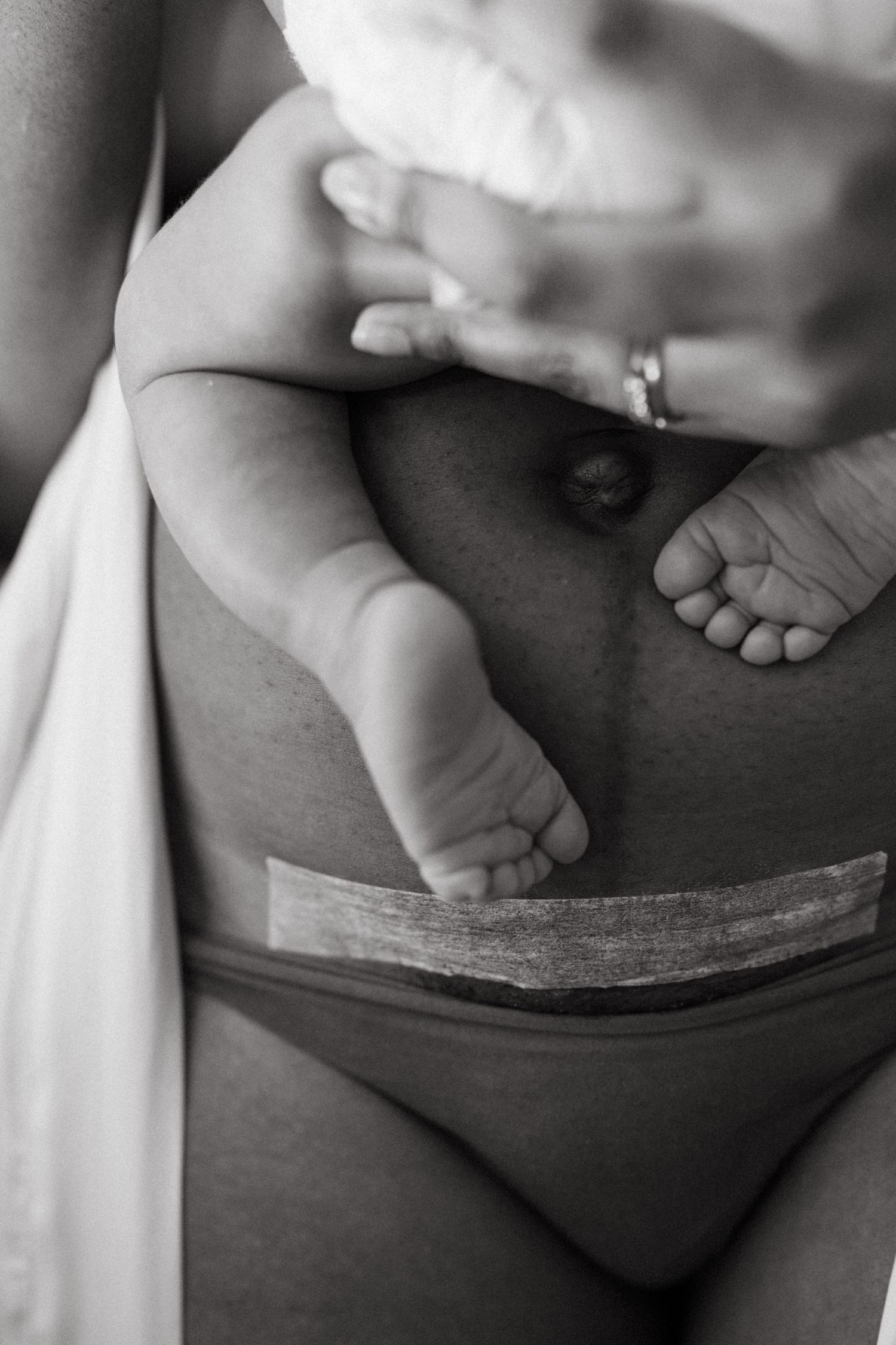 Black and white series focusing on the tiny feet of a newborn during nursing.