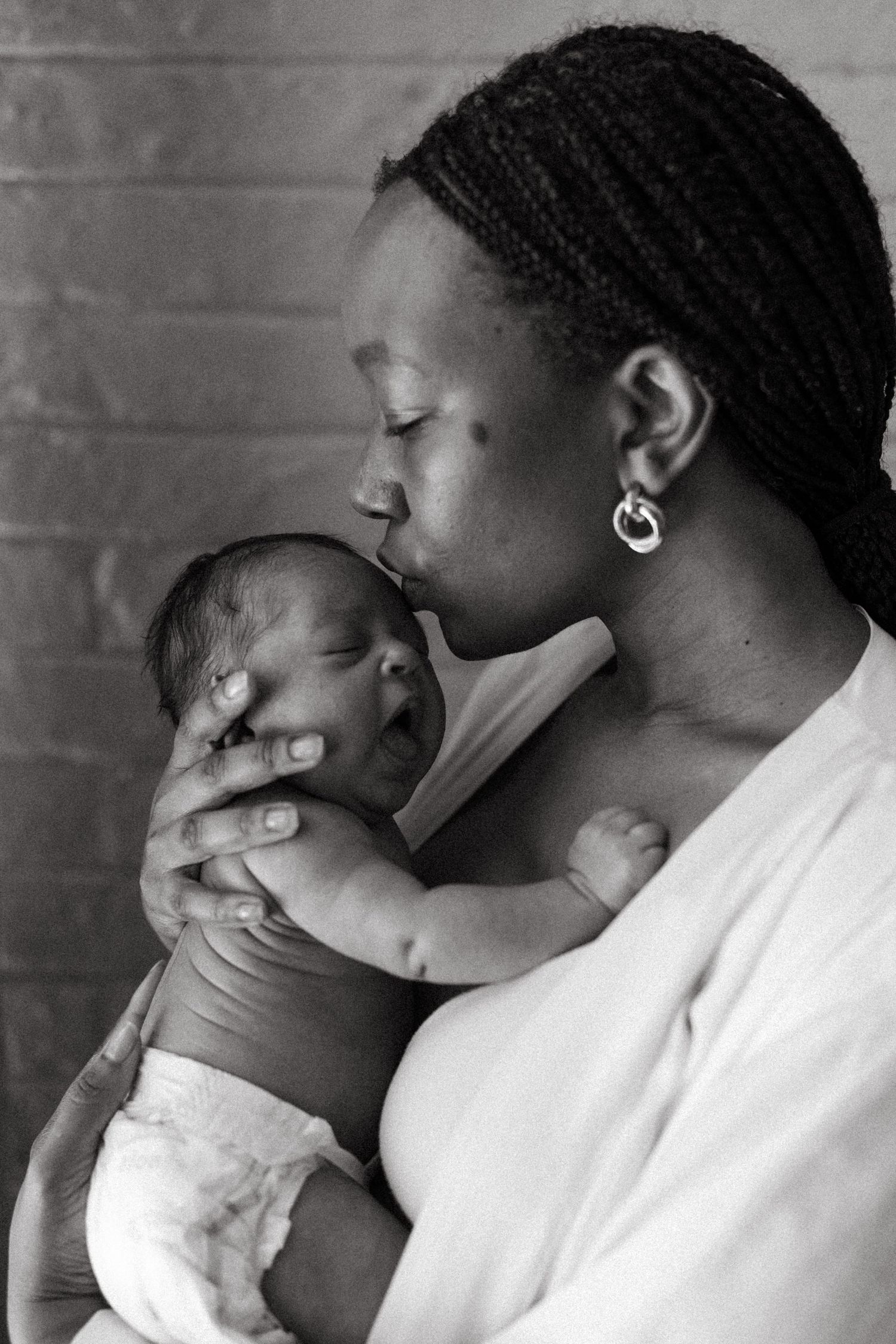 Black and white photos capturing loving moments between parent and newborn.