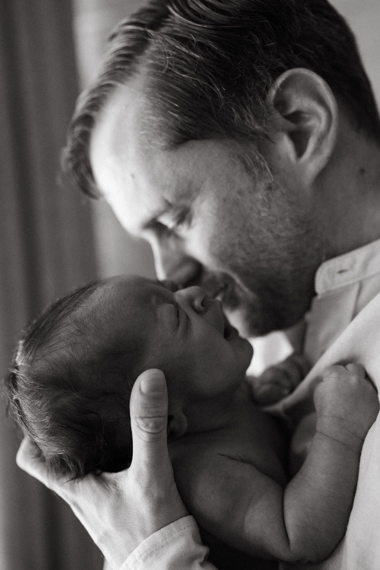A series of intimate black and white photos showing tender moments between parent and newborn.