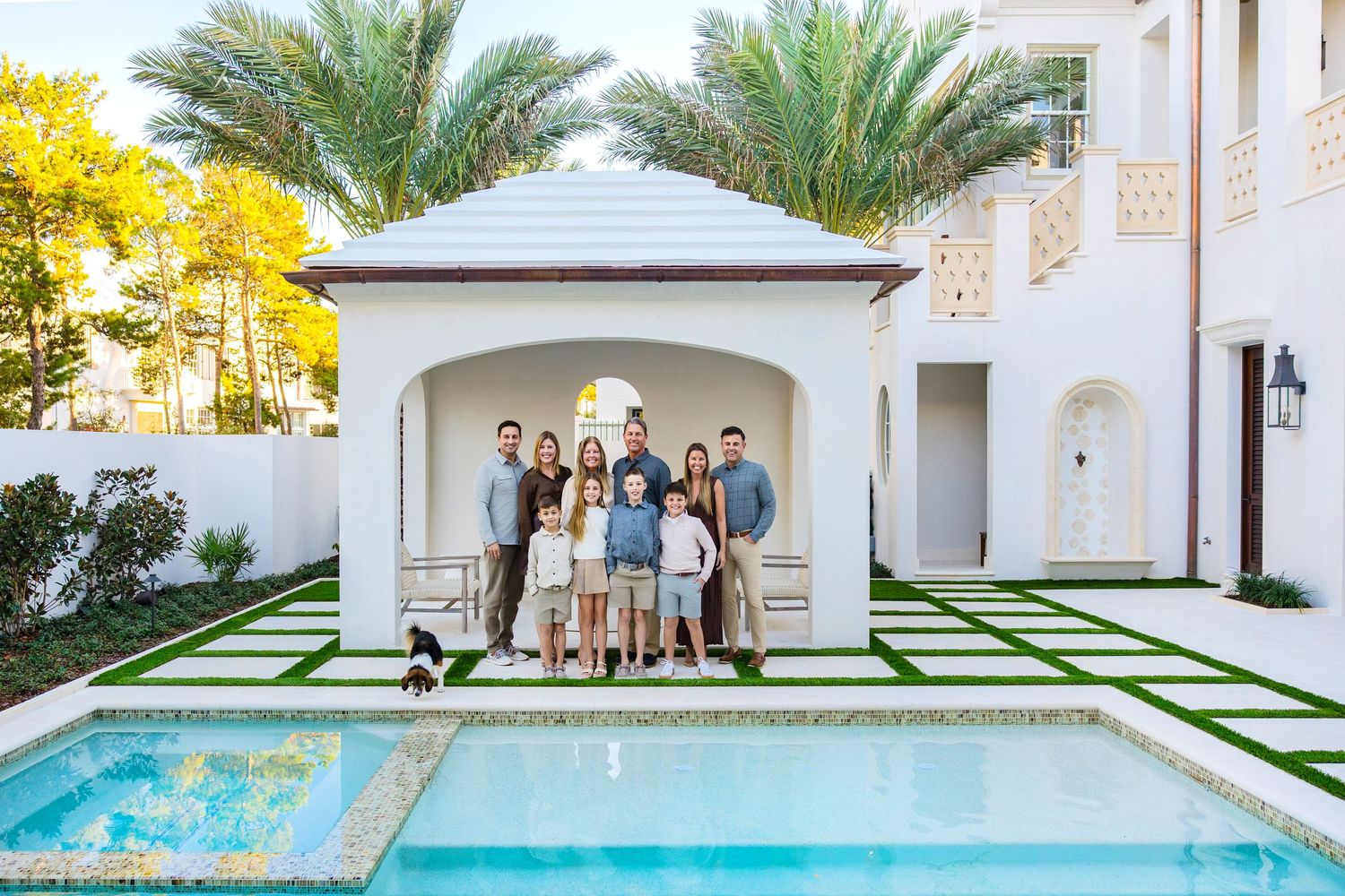 Modern white villa with palm trees and manicured lawn featuring contemporary outdoor seating areas and clean architecture.