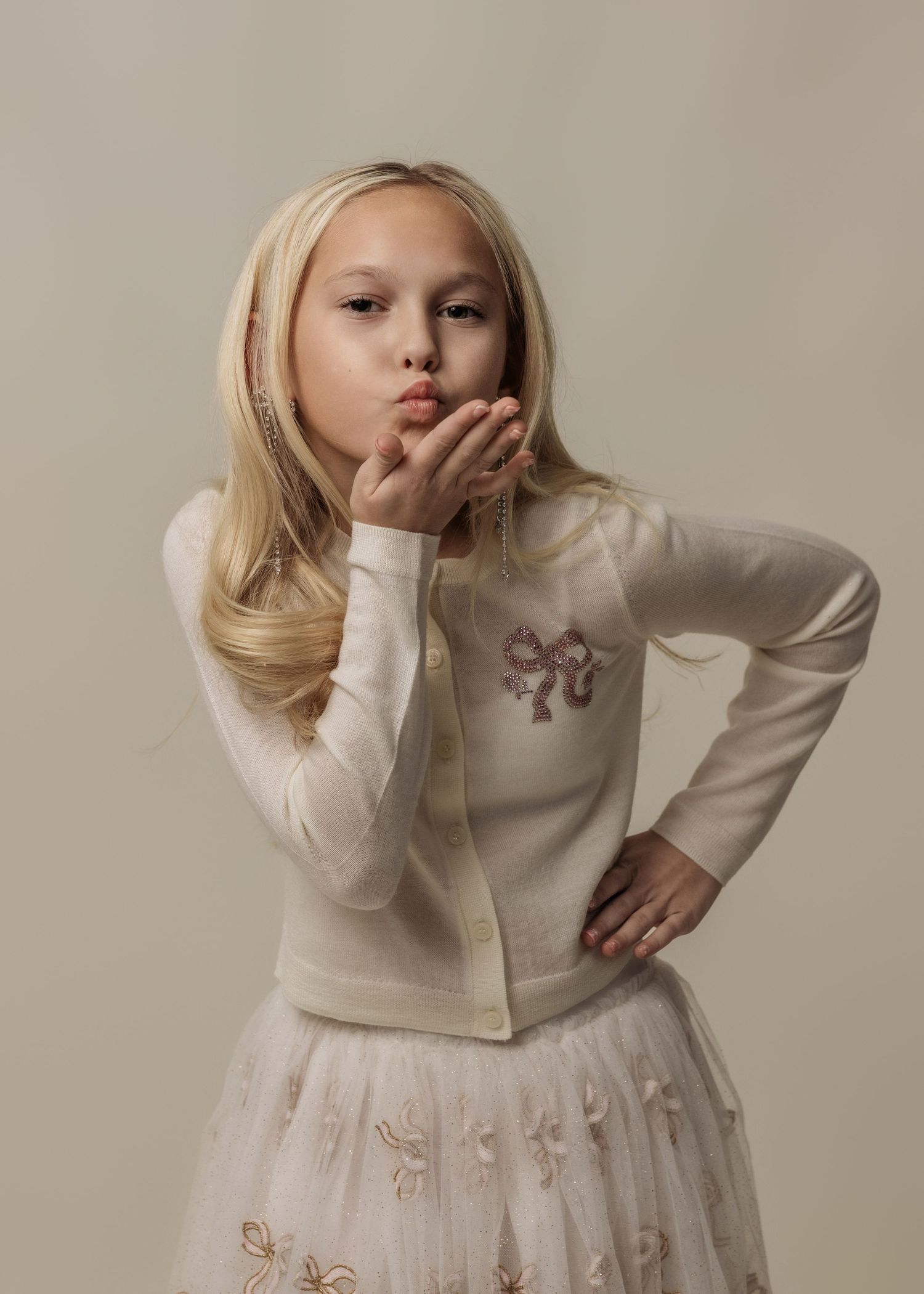 Fashion photos of a child wearing an elegant white dress with embroidered butterfly details.