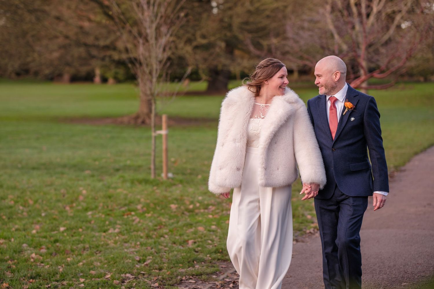 A couple shares a tender moment while walking together on a path during their winter wedding day.