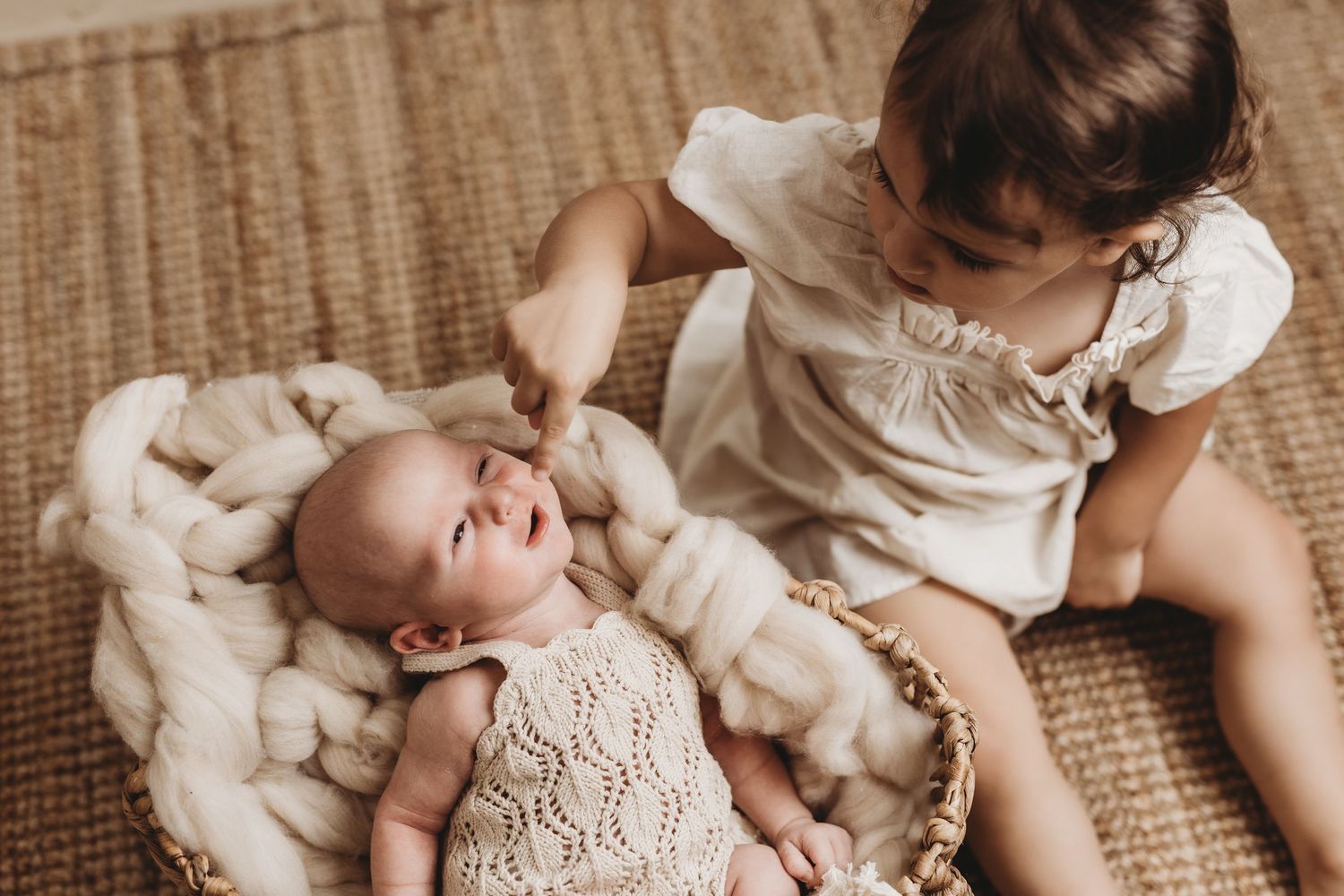 Family relaxing together on woven rug in casual setting.