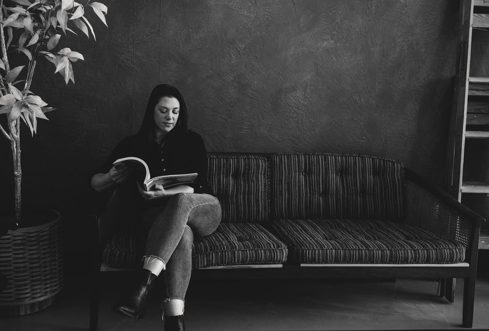 A dramatic black and white photo series shows a person lounging on a couch in various poses with maple leaves visible.