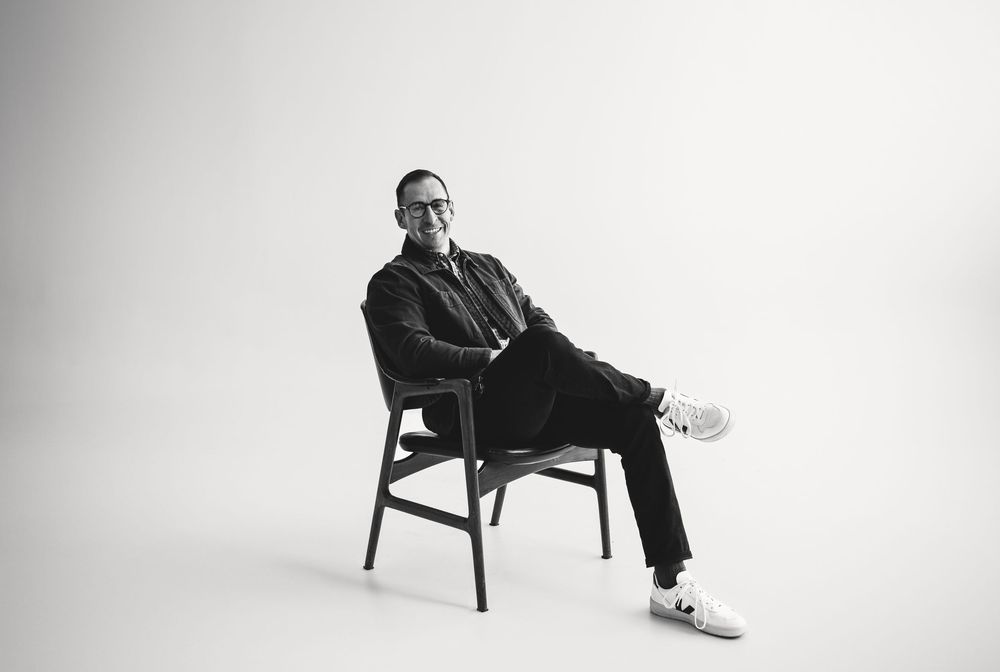 Black and white photo series showing a person sitting in various relaxed poses on a wooden chair against white backdrop.