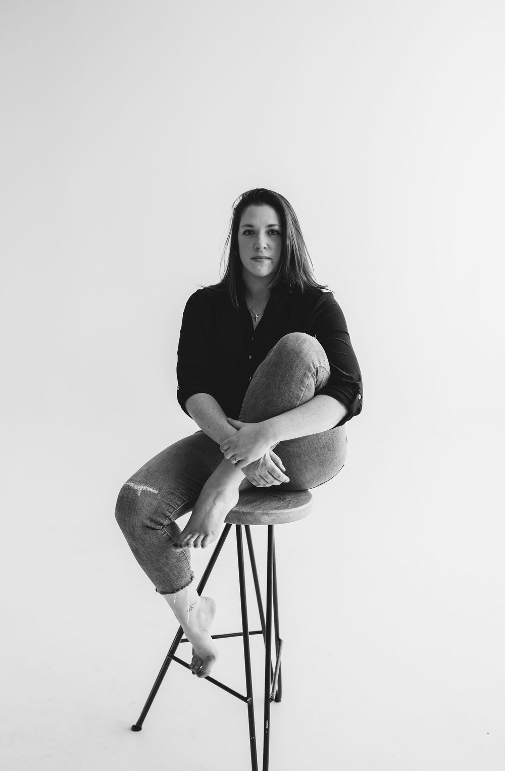 Minimalist black and white portraits showing a figure seated on a stool against white background.