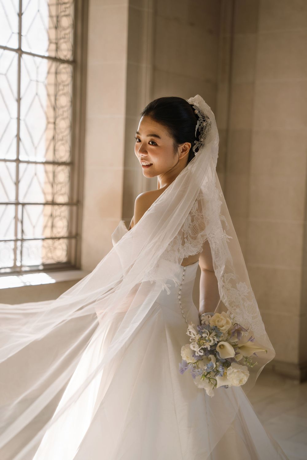 Ethereal bridal portrait series showing flowing white veil and bouquet in soft window light.