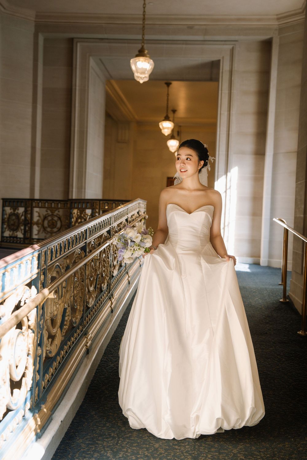 A series of elegant wedding dress photos in a grand hallway with ornate railings and hanging pendant lights.