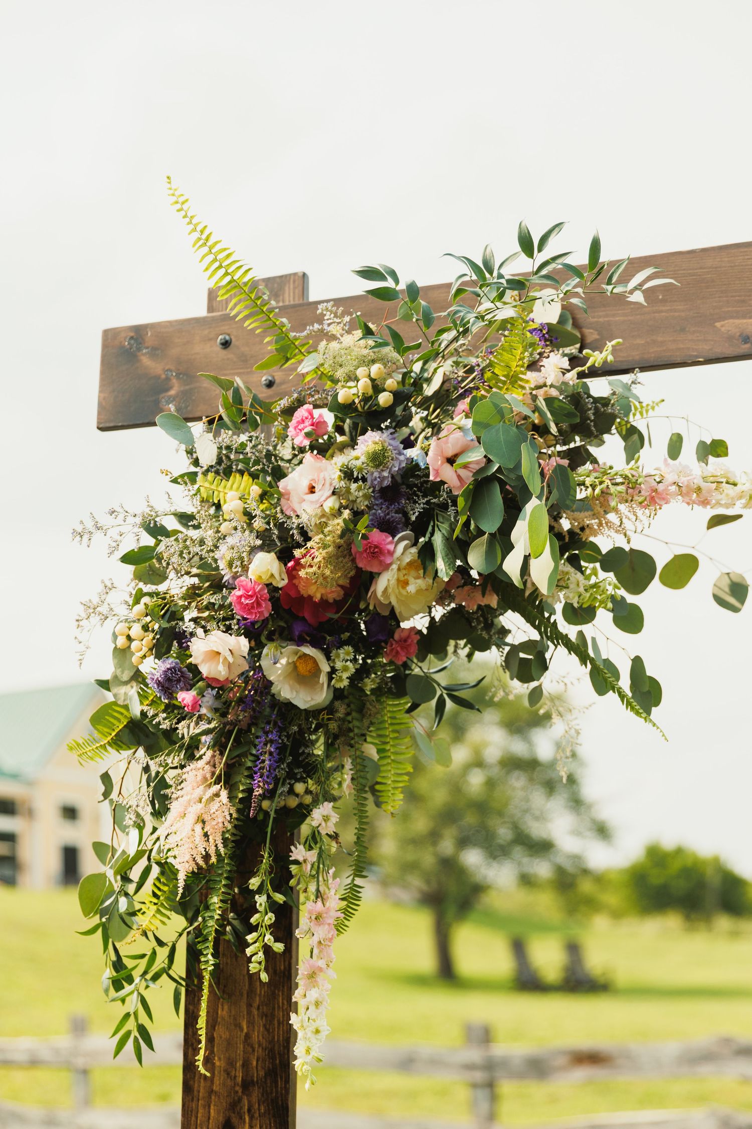 Wedding arch decorated with lush pink and white flowers, greenery and ferns.