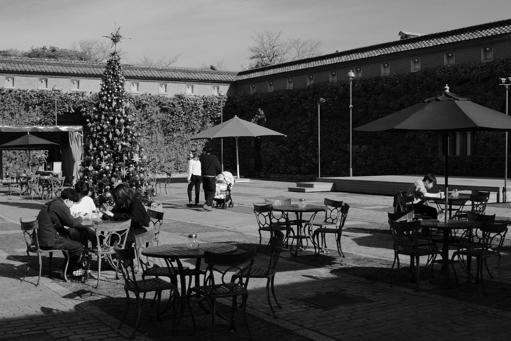 Black and white photographs showing outdoor cafe seating areas with tables and chairs arranged on a patio.