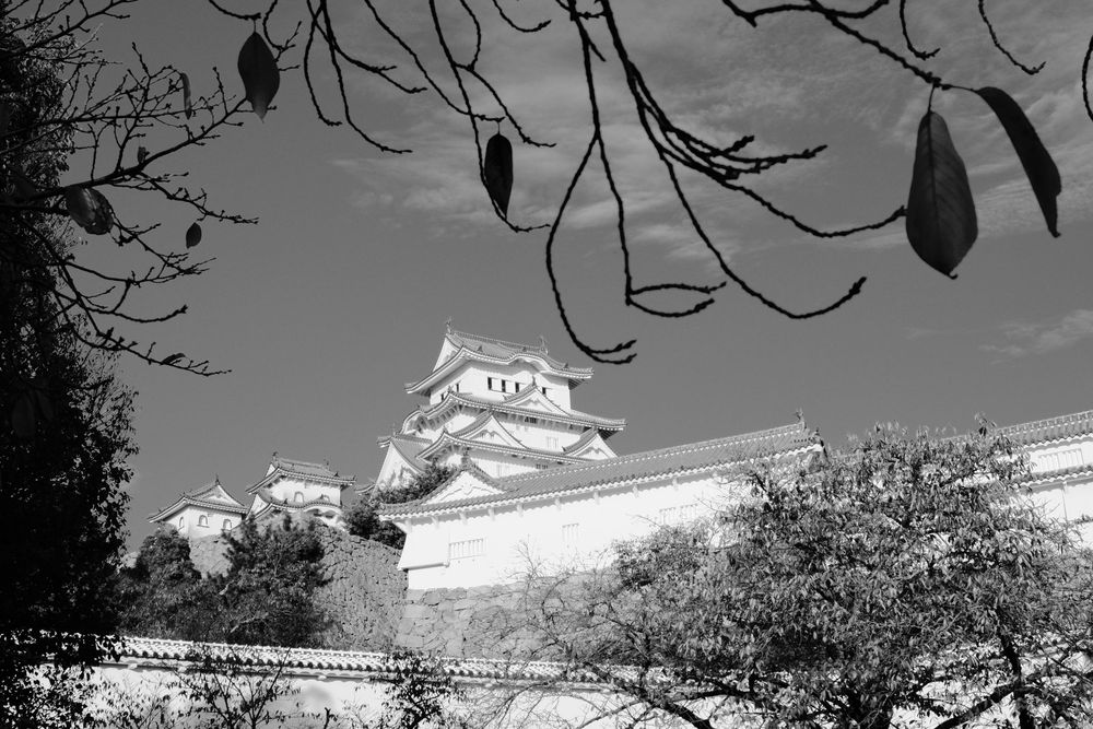 A black and white panoramic photo series showing the historic Japanese castle architecture and surrounding walls.