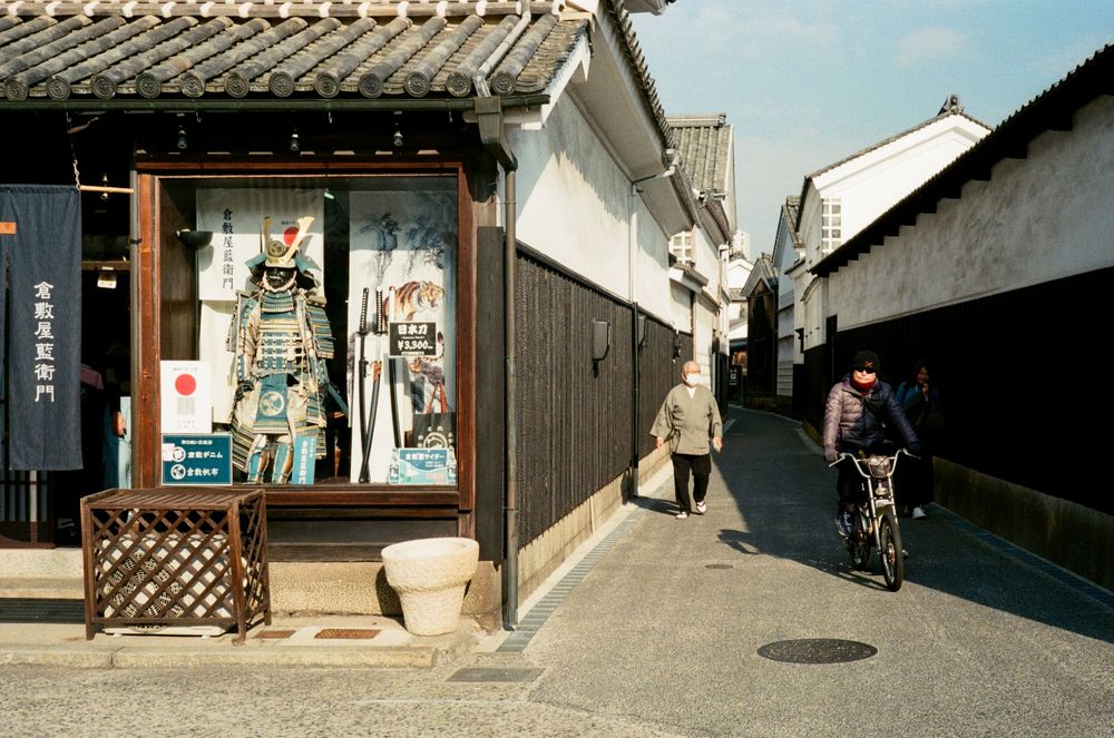 Narrow alleyway between traditional Japanese buildings with stone steps and wooden architecture in a historic district.